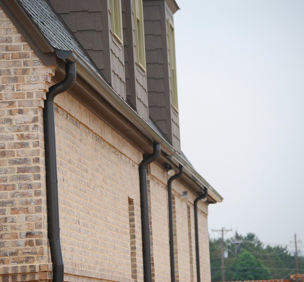 Gutter and downspout running down the side of a brick house